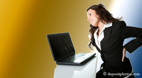 a person La Grande bending over a computer holding her back due to pain